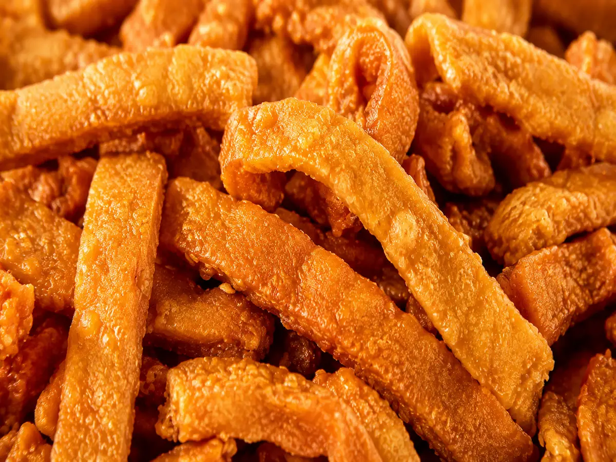 Extreme close-up of golden Nma-n-J Love Treats chin-chin showing its crisp texture, warm golden colour and appetising handmade appearance.